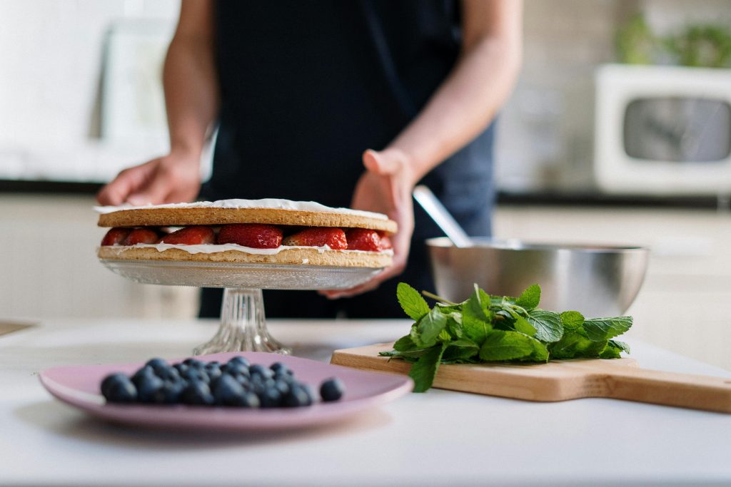 A homemade cake with strawberries and blueberries, garnished with mint. Perfect for a fresh dessert.